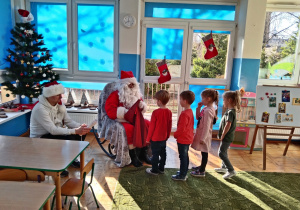 Mikołaj częstuje przedszkolaki cukierkami